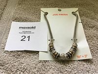 Full view of the Joe Fresh charm necklace on original card, showing chain and charms.