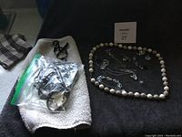 Photo showing the jewelry spread on a dark cloth including beaded necklace and assorted chains and earrings.