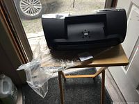 Sirius XM docking station main unit taped and on a small folding table near entrance door.