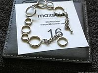 Full view of bracelet laid flat showing alternating hoop links and toggle clasp on black and white card background.