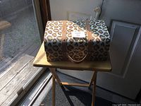 Photo of giraffe print suitcase on wooden folding table showing front and top with faux leather straps and handle