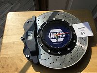 NAPA branded wall clock designed to look like a car brake rotor with caliper, angled view showing face and caliper