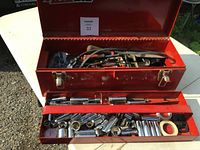 Open red metal toolbox showing lower removable tray with multiple sockets and extensions.