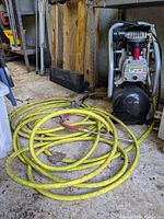 Husky black air compressor with yellow coiled hose in garage floor surroundings.
