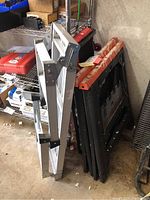 Folded aluminum bench seat next to sawhorses in a garage setting