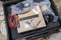 Top view of all components inside the black protective case, showing several cables and sensor parts along with the RH calibrator unit.