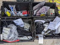 Overview photo of four black plastic bins filled with assorted hardware including zip ties, washers, bolts, gaskets, and electronic parts including a HP power supply.