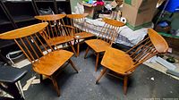 Five honey-finished spindle back chairs arranged in a semicircle on a workshop floor.