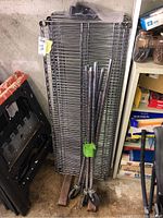 Unassembled metal wire shelves stacked vertically with caster wheel support poles bundled together in front.