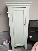 Full front view of vintage pantry cabinet showing door, knob, and crown molding.