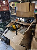 Closed cardboard box on a shelf containing multiple sandbag emergency lights with yellow bases and clear domes attached to olive green sandbags.