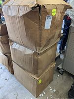 Three large stacked, worn cardboard boxes with visible rodent damage on top box, containing the safety lights.