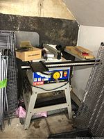 Full view of the Ryobi 10 inch table saw system with stand and various accessories placed on top and around it in a garage setting.