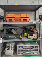 Shelf with orange roto tool case on top shelf along with chainsaw heads and hardware organizer below