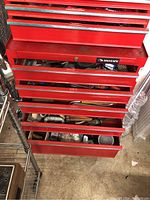 Red Husky branded metal tool chest showing partially opened drawers with tools and hardware inside