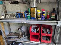 Shelf with hand saws, lubricant spray cans, level, hardware bins, arbor press and grease gun