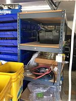 Metal shelving unit fully assembled with items stored on shelves in a garage setting, showing particle board shelves supported by perforated metal frame.