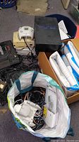 Bins with multiple consoles and bag of cables and Dreamcast controller visible