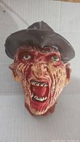 Front view of the Freddy Krueger head statue showing full facial detail and fedora hat.