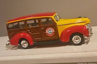 Side view showing red and yellow Ford Woody with wood panel detail and Arm & Hammer logo on door.