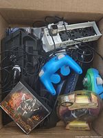 Top view of lot showing blue and green Nintendo GameCube controllers, cables, 'Lands of Lore III' PC game, and boxed 'Interface 6' accessory.