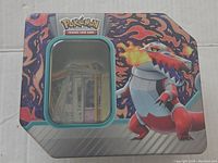 Photo of closed metal tin with Pokémon logo and fire-type Pokémon artwork on lid.