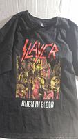 Front side of black Slayer Reign In Blood album art T-shirt showing logo and graphic design.