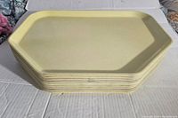 Stack of 8 yellow octagonal plastic cafeteria lunch trays with visible wear on edges.