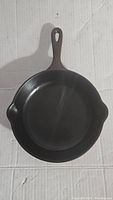 Top view of the cast iron dark brown enamel skillet showing the interior cooking surface and handle with hanging hole.