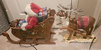 Side view of Santa Claus seated in ornate sleigh with visible gift sack and harnesses on reindeer