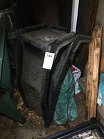 Pair of black steel auto ramps leaning against a surface, showing their side profile and signs of rust and dirt, with perforated traction holes visible