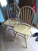 Pair of solid wood chairs with curved backrests and vertical slats shown side by side on wooden floor.