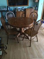 Full view of the solid wood round pedestal dining table with 4 matching chairs surrounding it.