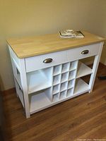 Front view showing butcher block top, two drawers, central wine cubby grid and bottom shelf