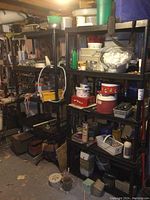 Photo showing two black resin shelving units placed side by side against basement wall filled with various storage items such as containers, tools, and household supplies.