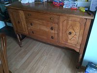 Full front view of the vintage wooden sideboard showing two cabinets and three drawers with metal ring pulls.