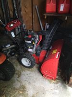 Front-left view shows red discharge chute, black impeller housing, engine atop red auger housing