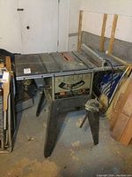 Front-left view of the Craftsman table saw in basement, shows overall size, blade slot, and legs with visible wear and dust.