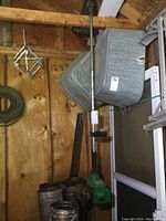 Full view of the Weed Eater gas weed trimmer leaning against wooden wall with garden tools in the background.