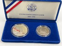 Two US Liberty proof coins in capsules inside blue velvet display case with silk lining and USA emblem