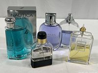 Five perfume and cologne bottles arranged with box, colors blue, purple, clear, and pale yellow.