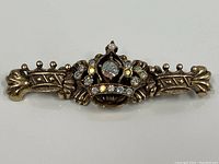 Front view of the vintage gold tone crown brooch pin with multiple clear and iridescent crystal stones.
