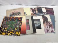 Overview of 13 vintage vinyl albums in a pile, covers showing diverse artistic designs including abstract and photographic.