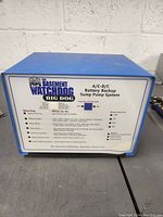 Front view of The Basement Watchdog Big Dog A/C-D/C Battery Backup Sump Pump System showing brand, model, indicator lights, switch, and usage instructions.