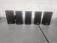 Front view of five Bose speakers, showing two smaller and three larger units in black with Bose logo