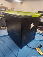 Side view of the Copernicus Tech Tub showing black case with lime green lid and a logo featuring a cartoon character.