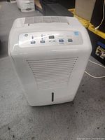 Front view of the white GE dehumidifier showing vent grill and control panel on top.