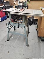 Full side view of Delta table saw on stand showing power cord, legs, and flat work surface.