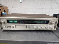 Full frontal view showing analog meter and tuner frequency display, control knobs for power, rec level, playback, and recording.