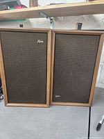 Pair of Fisher speakers showing front wooden frames and brown fabric grille with Fisher logo